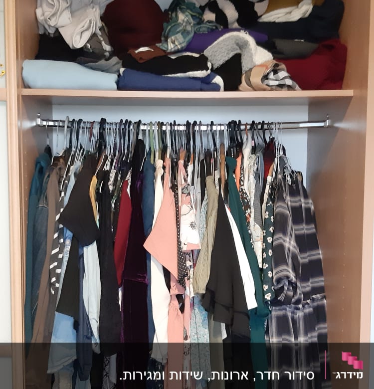 ארון בגדים עם בגדים תלויים ומקופלים על מדפים